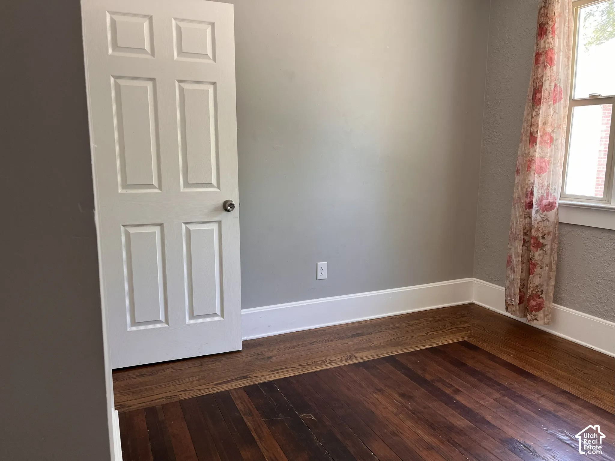 (Front Unit) Hardwood flooring with a rich finish, crisp white trim, and a classic paneled door