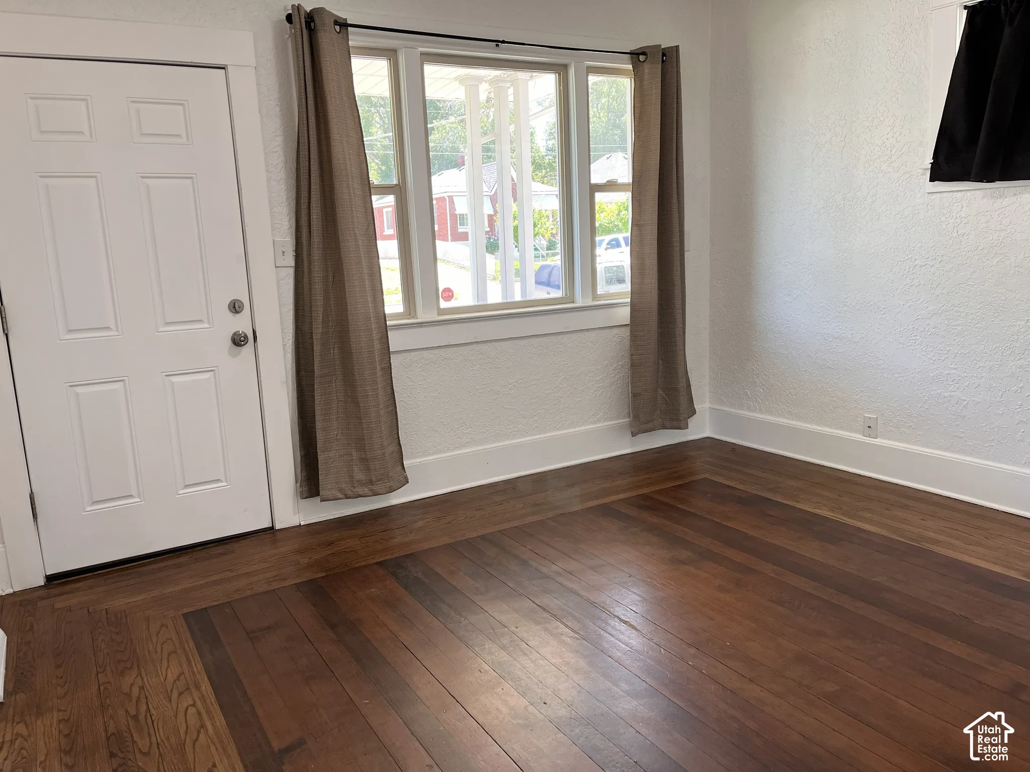 (Front Unit) Rich wood-finish flooring, white paneled door, and bright window with white trim
