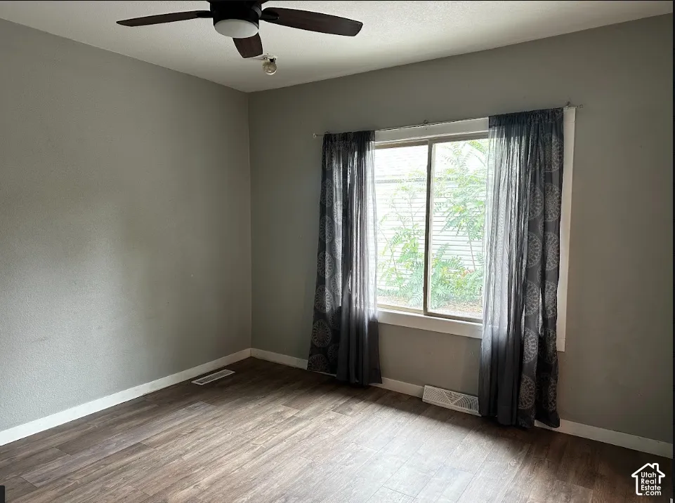 Wood-finish flooring, neutral wall tones, and a ceiling fan with integrated lighting