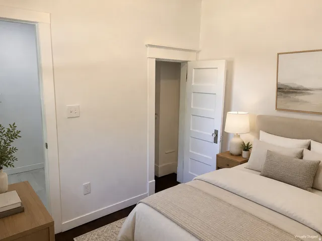 Dark wood-finish flooring with white trim, a four-panel interior door, and light-colored walls