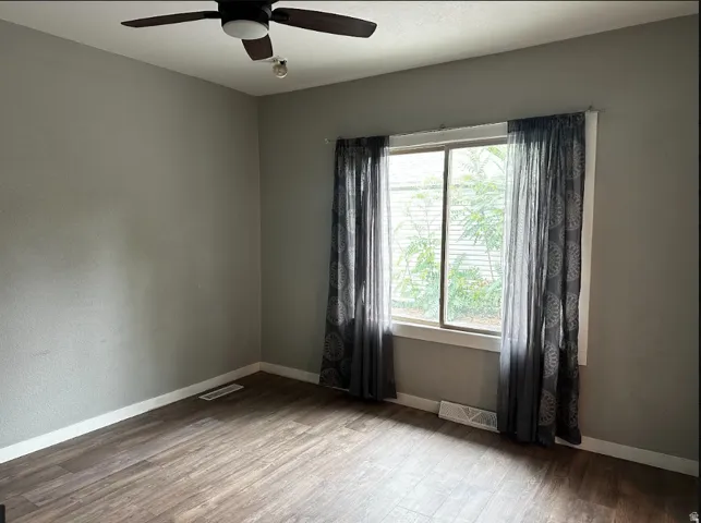 Wood-finish flooring, neutral wall tones, and a ceiling fan with integrated lighting