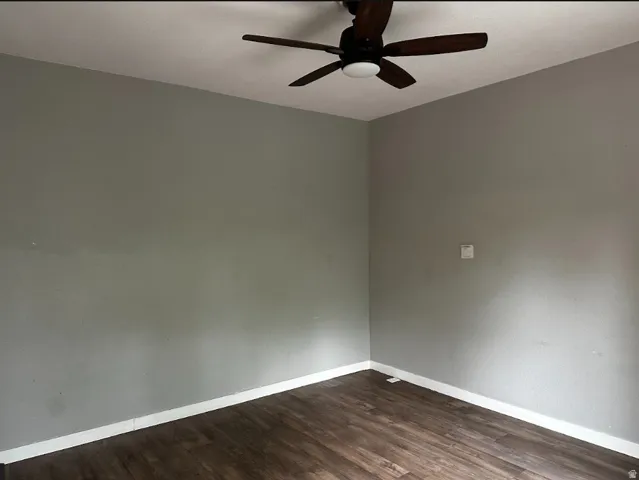 Wood-finish flooring with white trim and a ceiling fan