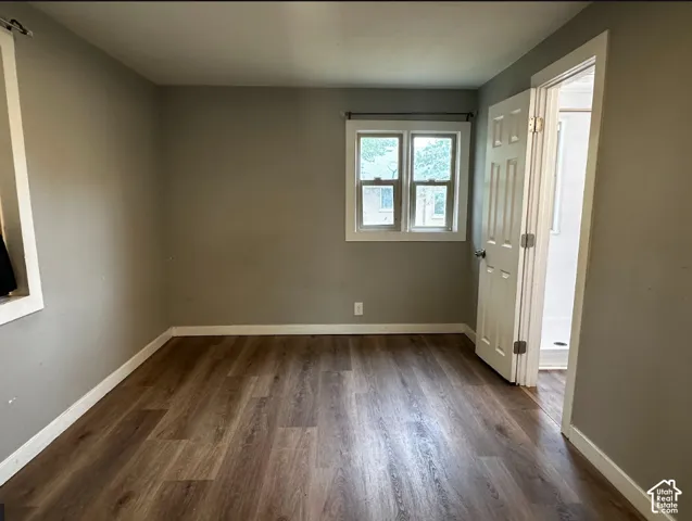 Wood-finish flooring with white trim, neutral wall color, and a multi-pane window
