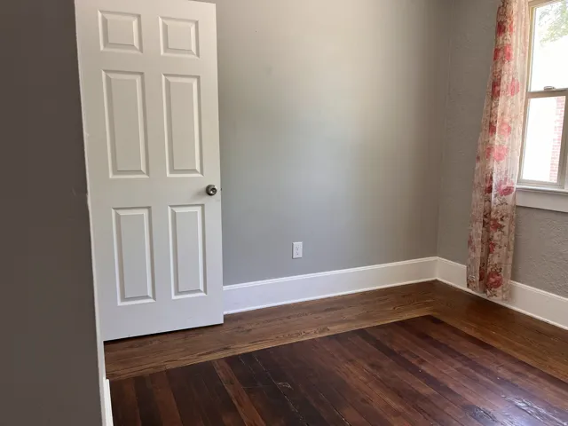 Hardwood flooring with a rich finish, crisp white trim, and a classic paneled door