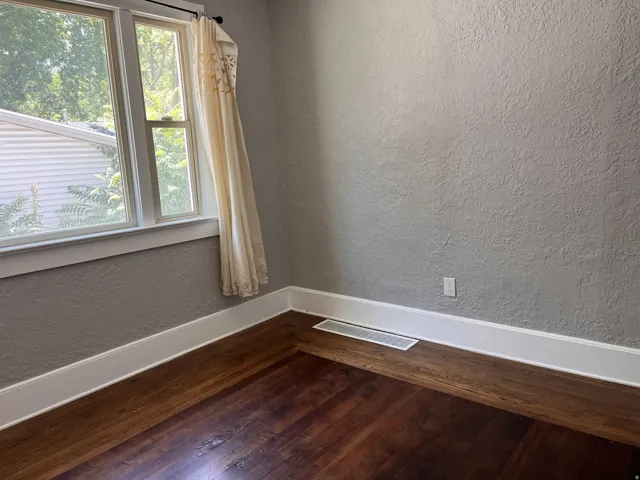 Hardwood flooring, painted textured walls, white trim, and double-hung windows