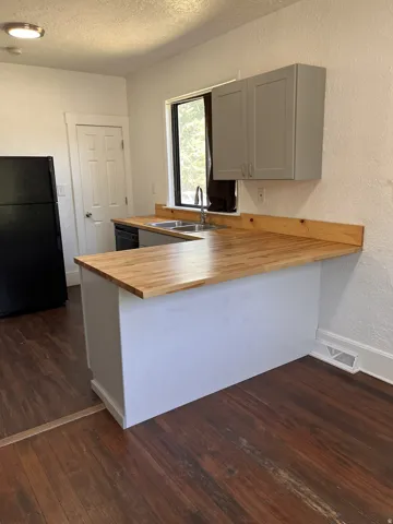 U-shaped kitchen layout with wood-finish countertops, stainless steel sink, and gray upper cabinetry