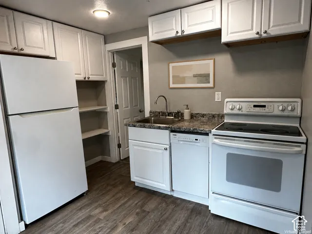 Kitchen featuring white cabinetry, wood-finish flooring, a stainless steel sink, and white appliances
