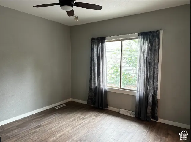 Wood-finish flooring, neutral wall tones, and a ceiling fan with integrated lighting