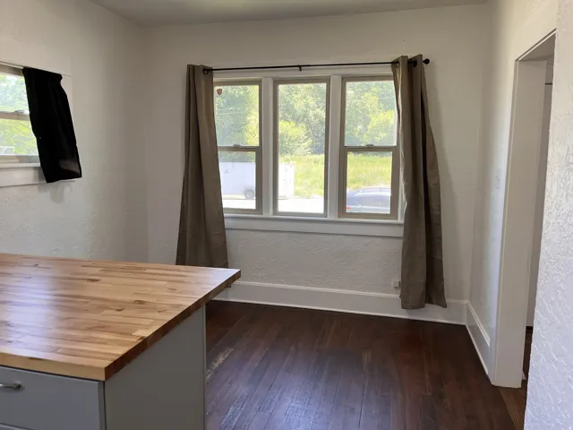 Wood-finish butcher block countertop, white painted walls, natural wood flooring, and white window trim
