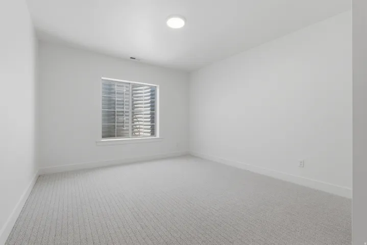 White walls, light-colored carpet, and a single window with blinds