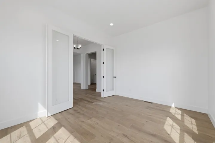 White walls, light wood-finish flooring, and recessed lighting