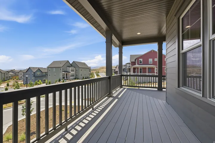 Covered balcony featuring composite decking and a dark-toned railing, with siding and windows visible