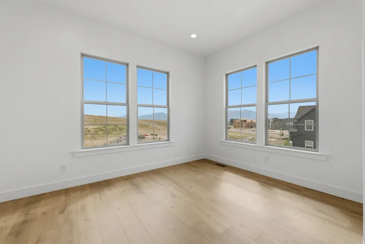 Light-filled room featuring five large windows with gridded panes, recessed lighting, and wood-finish flooring