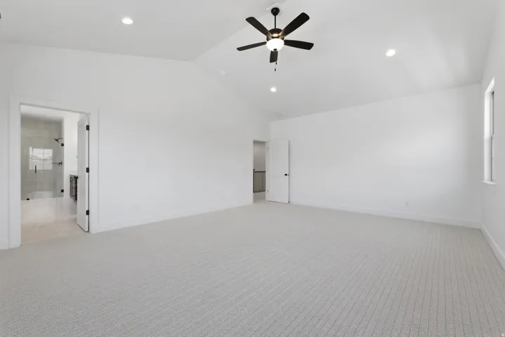 Primary suite. Vaulted ceiling with a ceiling fan, recessed lighting, and light-toned carpeting