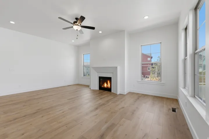 Spacious room featuring wood-finish flooring, a contemporary fireplace, and multiple windows