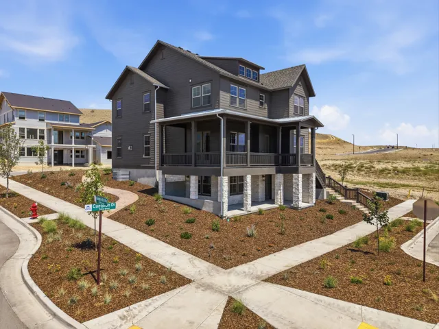Three-story exterior with dark gray siding, stone pillars, and multiple windows