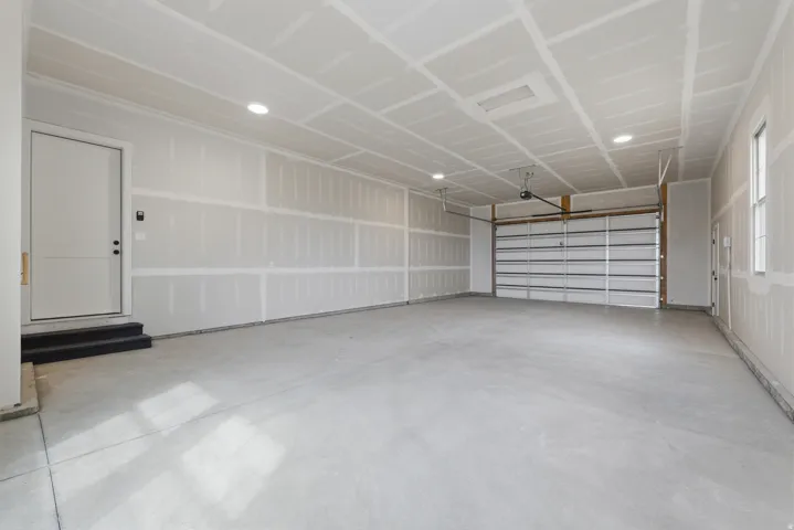 Spacious garage featuring a concrete floor, overhead lighting, and a roll-up garage door