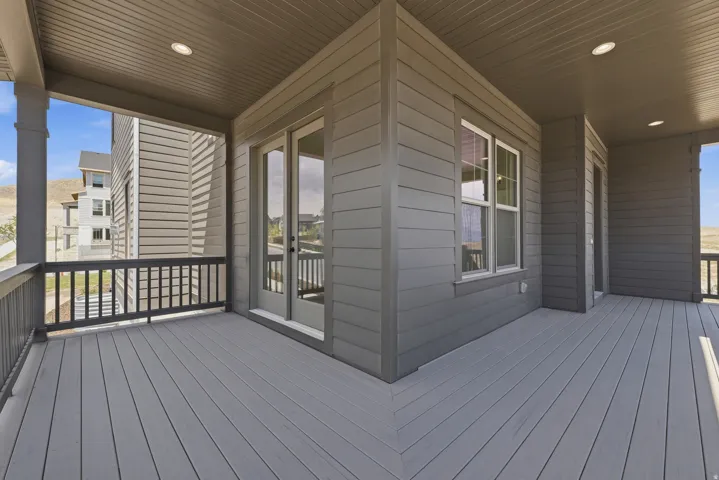 Spacious covered deck featuring composite decking, recessed lighting, double French doors, and a window