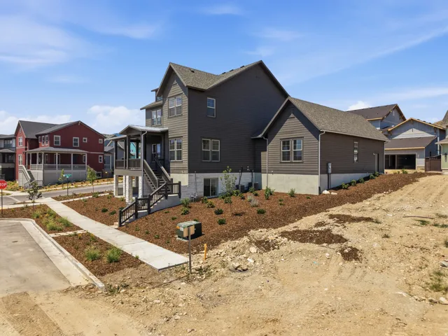 Multi-level exterior with dark gray siding, covered porch entrance with white stone accents, and a separate detached structure