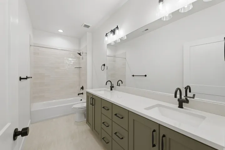 Dual vanity with stone-finish countertops, matte black fixtures, and integrated sinks