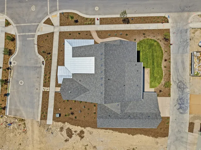Asphalt shingle roofing, metal roofing accents, and a curved lawn area