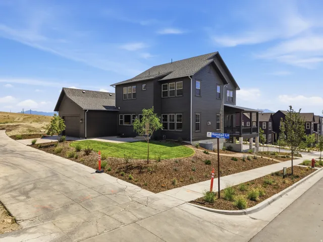 Multi-story residence featuring dark siding, a covered front porch, and an attached two-car garage