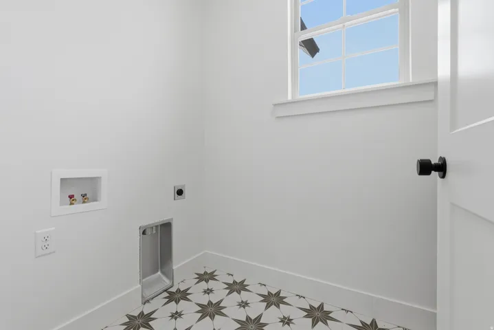 Patterned floor tiles, white walls, white trim, white window, and black door hardware