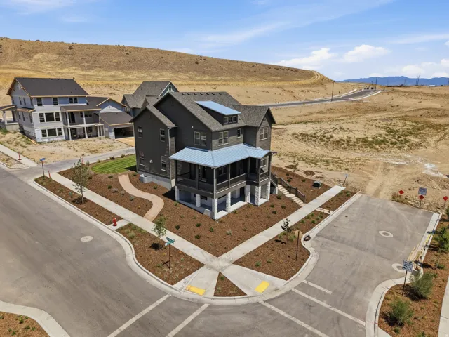 Corner lot with new landscaping, featuring a covered porch, stone accents, and a dark-toned exterior