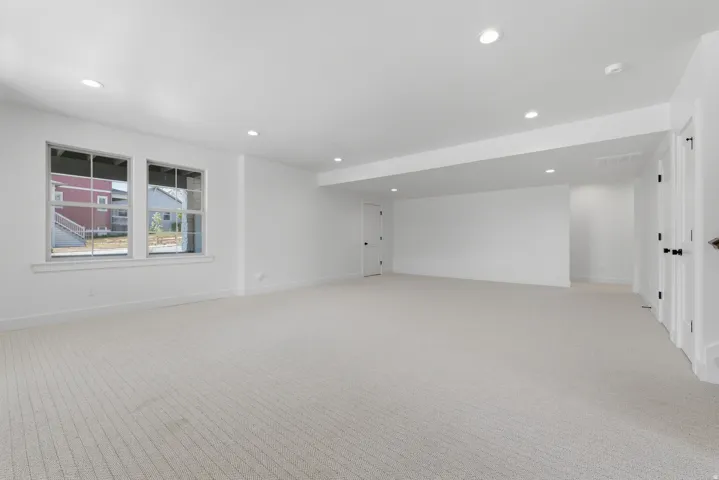 Expansive room featuring recessed lighting, light-colored carpeting, multiple windows, and crisp white walls
