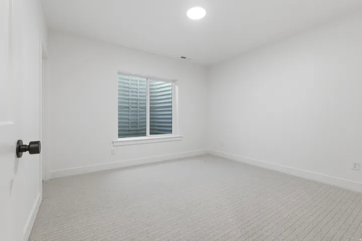 Recessed window with white trim, light-toned patterned carpeting, white painted walls, and a flush-mounted ceiling light fixture