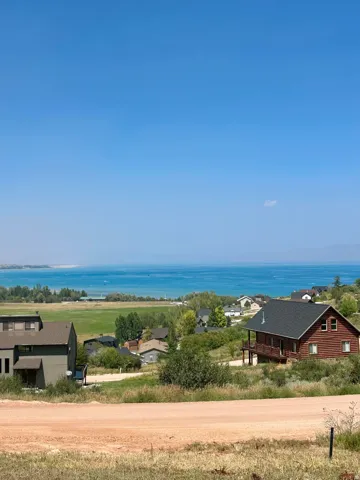 Expansive water body, surrounding green landscape, and multiple residential structures