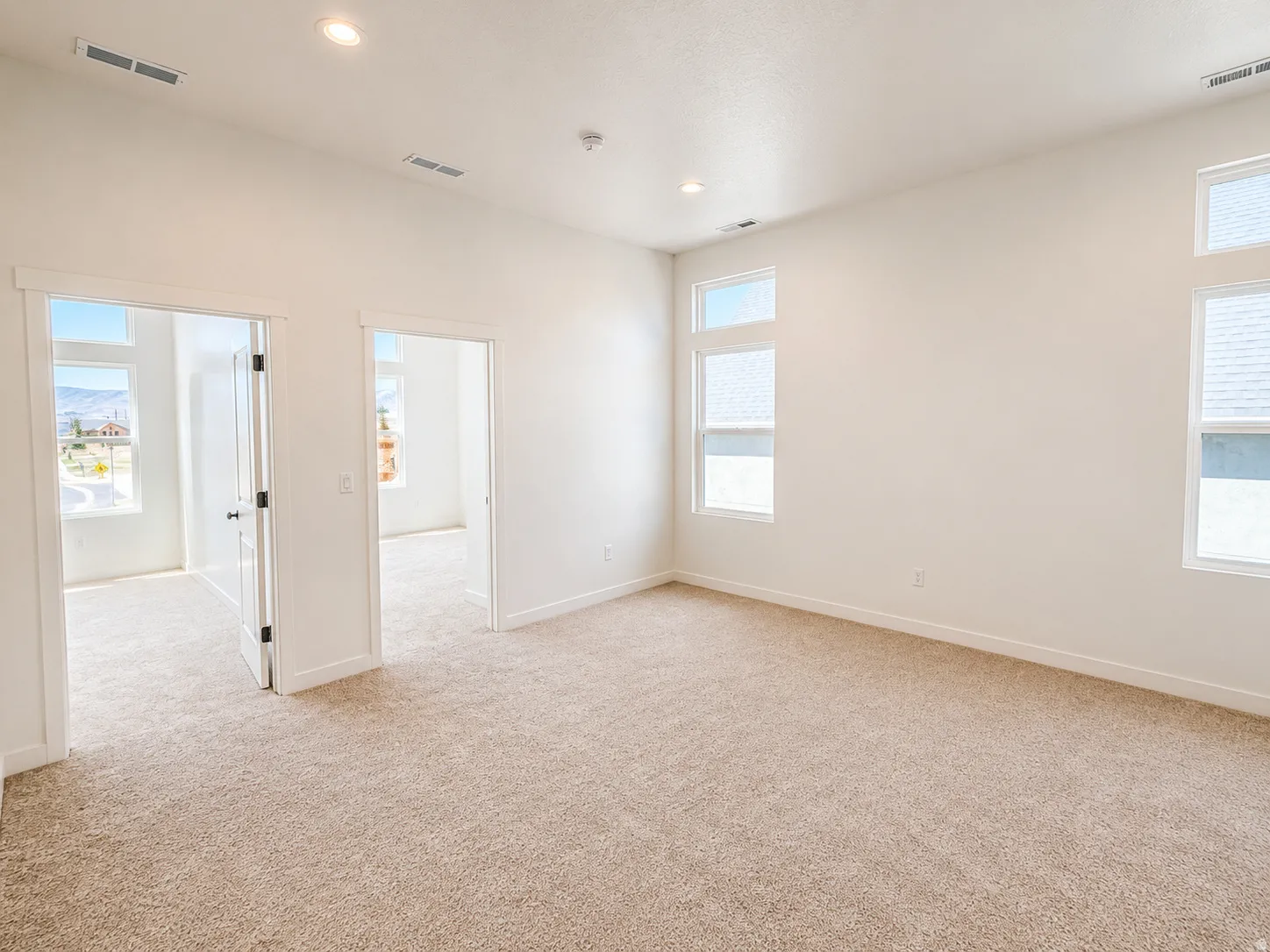 Carpeted room with recessed lighting and multiple windows