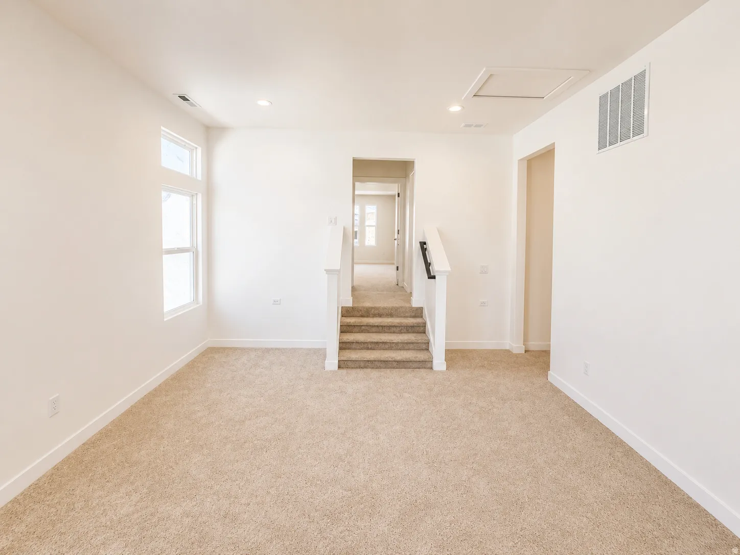 Plush carpet flooring, recessed lighting, white wall paint, white trim, and white railings with dark posts