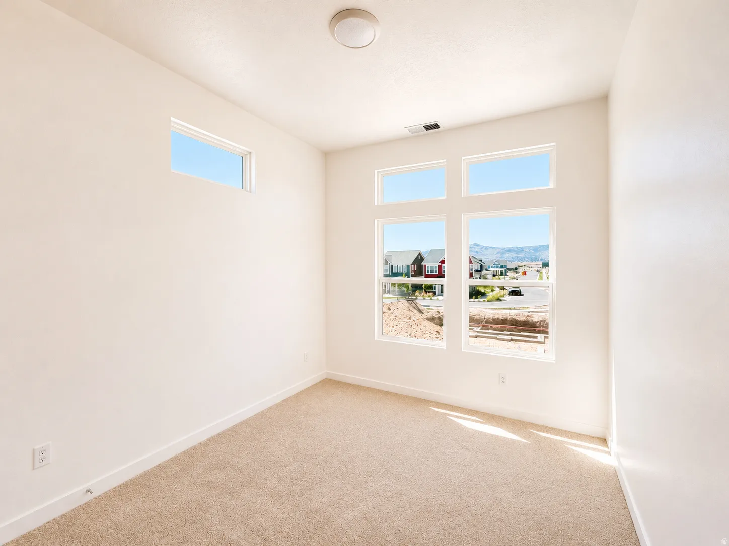Carpeted room featuring multiple windows, a ceiling-mounted light fixture, and white wall finishes