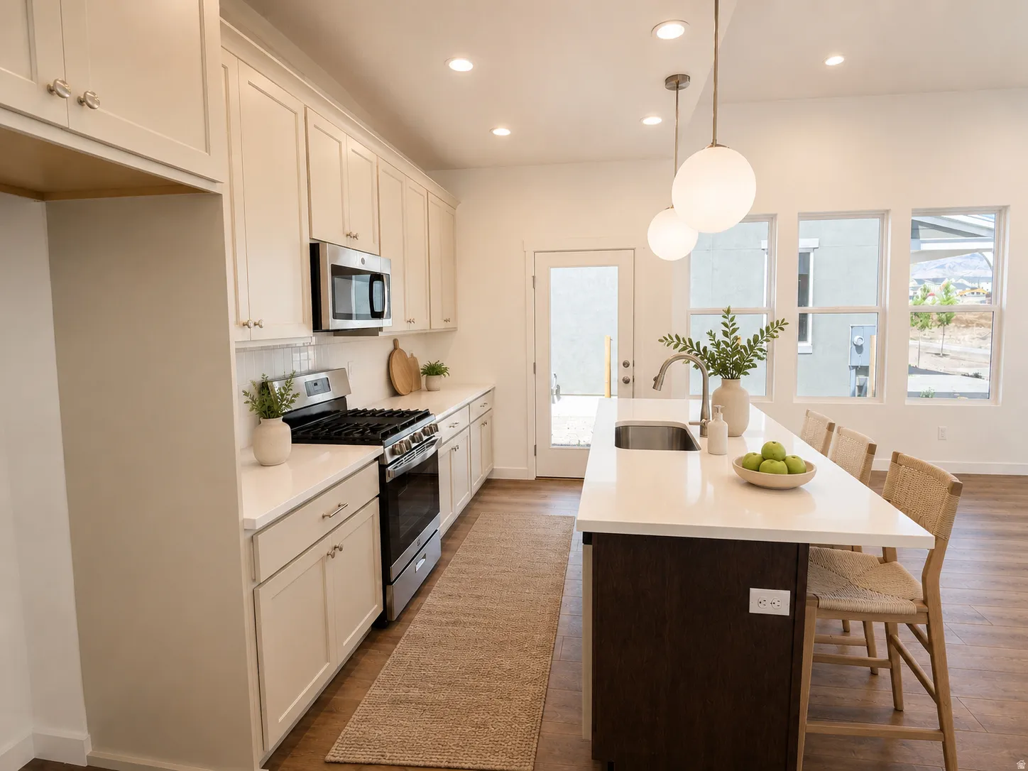 Kitchen featuring white shaker cabinetry, stainless steel appliances, white quartz countertops, and a center island with a built-in sink