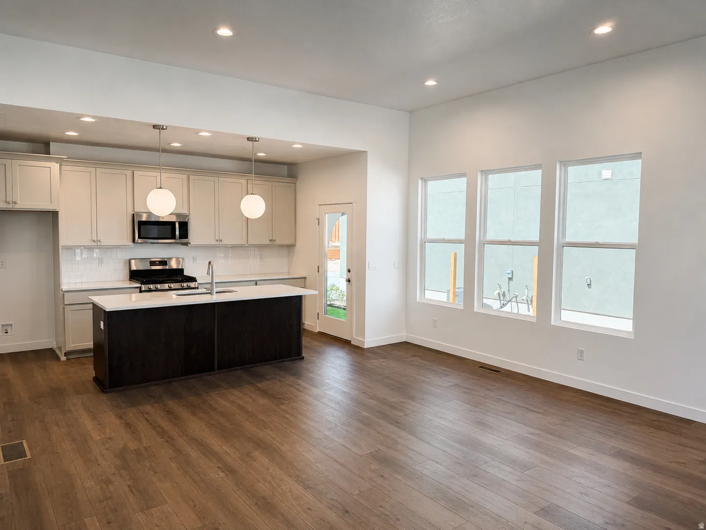 Kitchen featuring light-toned cabinetry, stainless steel appliances, a center island with a white countertop, and pendant lighting