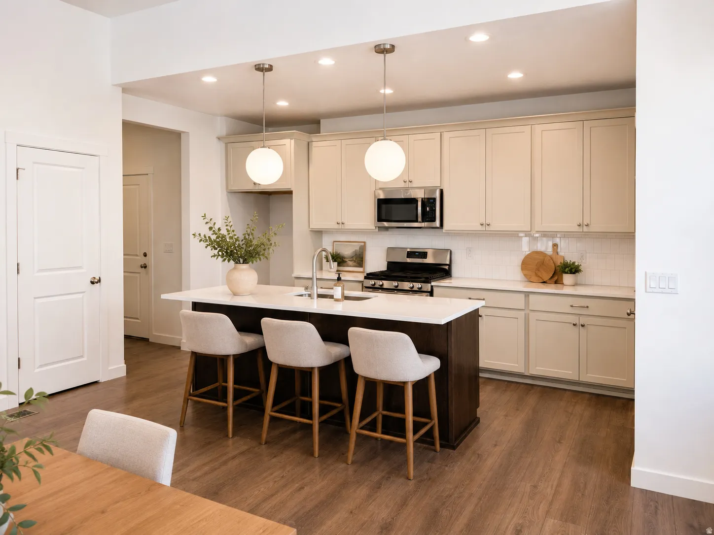 Kitchen featuring an island with a white countertop, stainless steel appliances, wood-finish flooring, recessed lighting, and pendant lighting