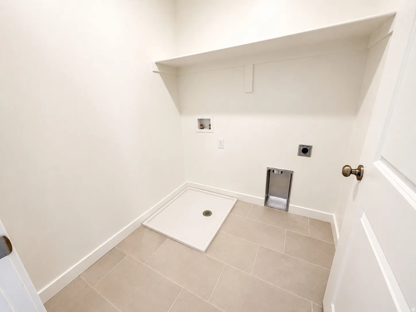Dedicated laundry area with durable tile flooring and a utility sink basin