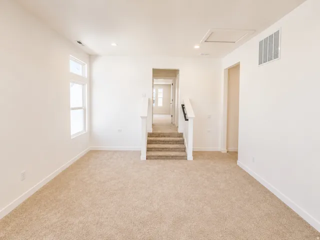 Plush carpet flooring, recessed lighting, white wall paint, white trim, and white railings with dark posts
