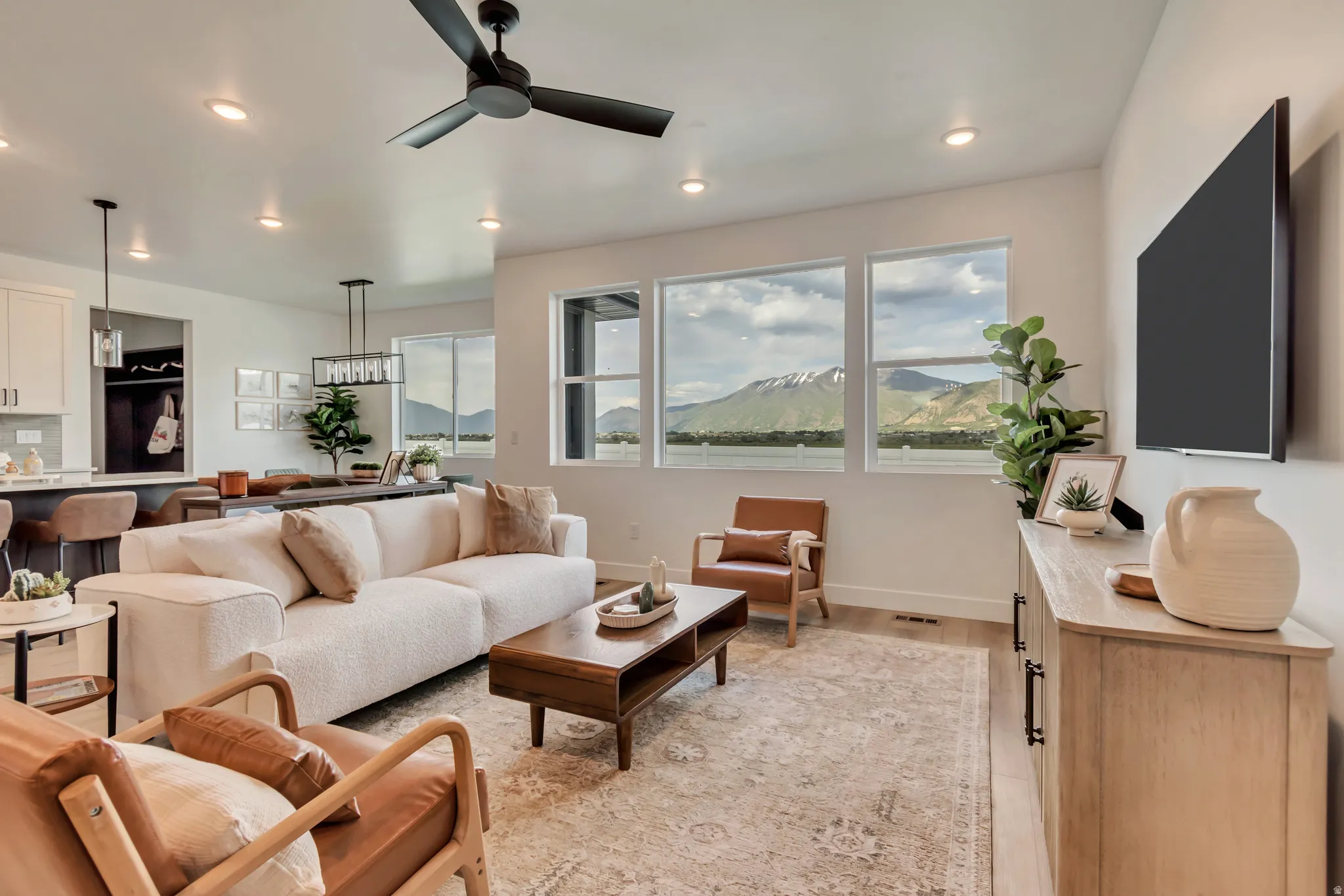 Recessed lighting throughout, multi-pane windows with mountain scenery, wood-finish flooring, a ceiling fan, and a built-in media console