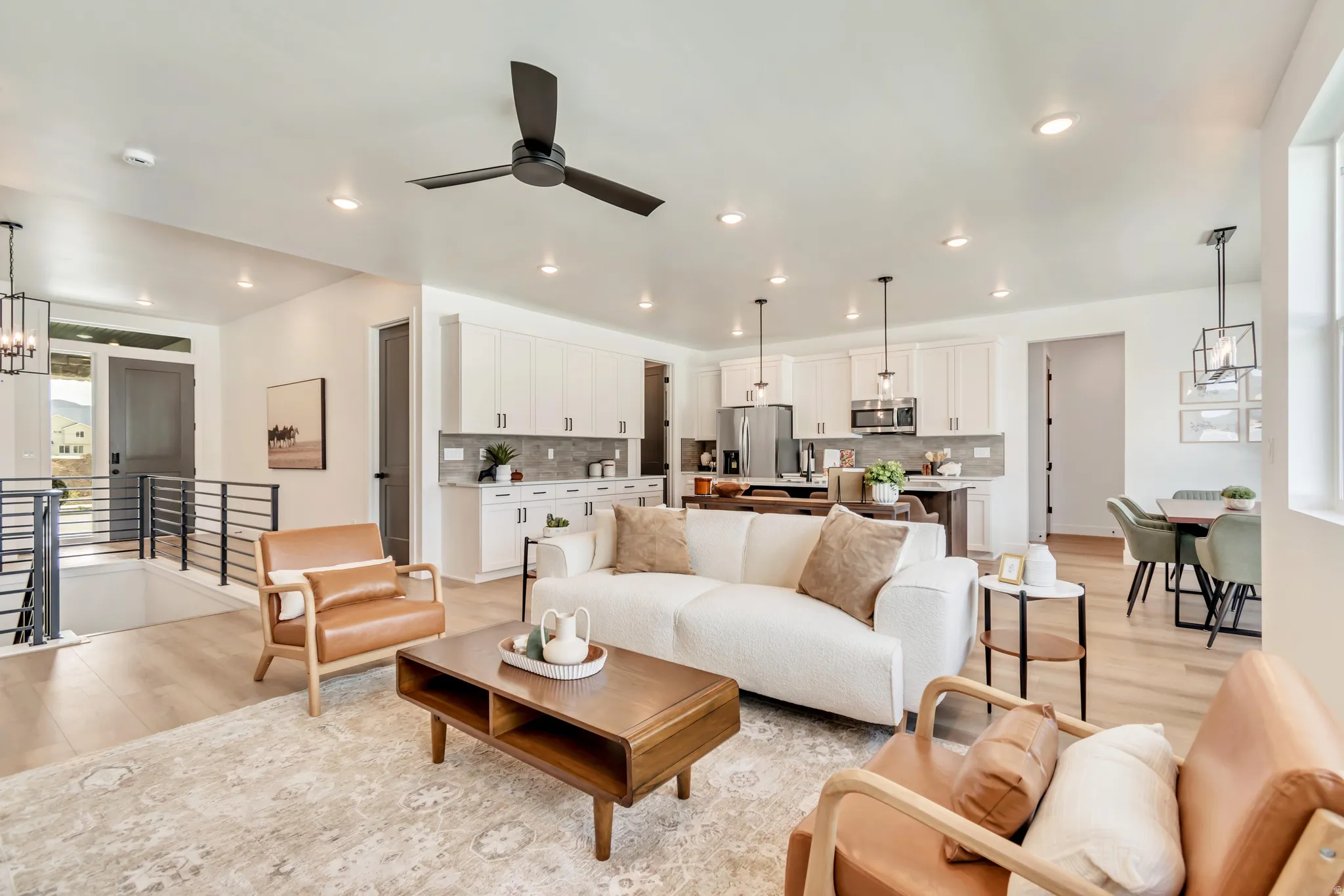 Open-concept living space with light wood-finish flooring, recessed lighting, and a contemporary ceiling fan