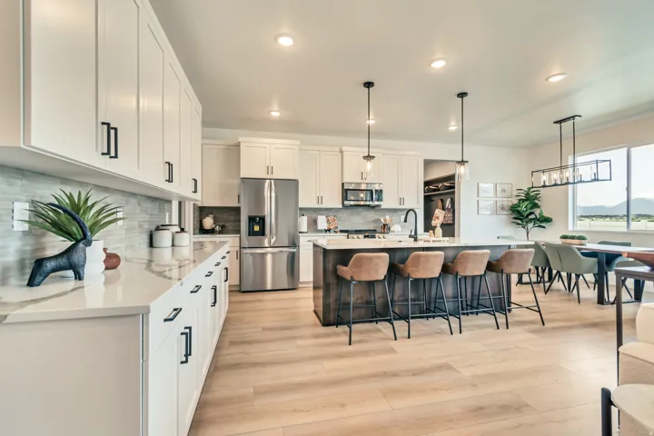 Bright kitchen featuring white cabinetry, stainless steel appliances, a center island with pendant lighting, and wood-finish flooring