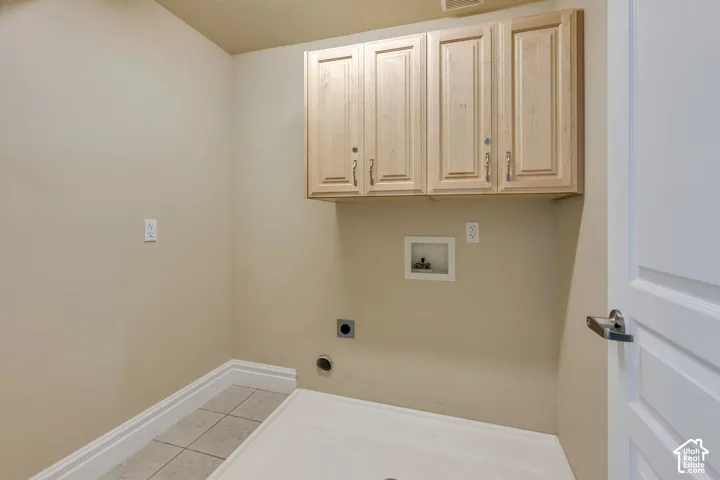 Wall-mounted cabinetry, tile flooring, and a utility sink base