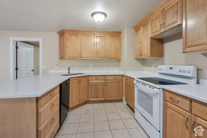 U-shaped kitchen featuring light wood cabinetry, white countertops, tile flooring, and a full suite of white appliances