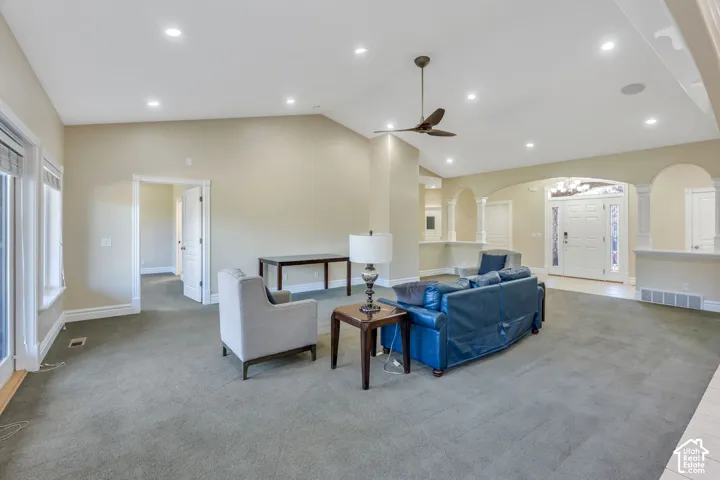 Spacious living area featuring a vaulted ceiling with recessed lighting, ceiling fan, and large windows
