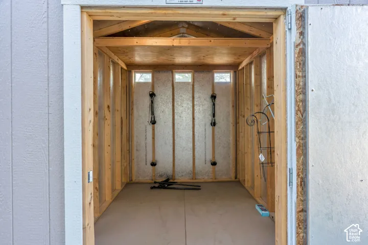 Interior shed space featuring exposed wood framing, wood paneling, and a light-colored floor