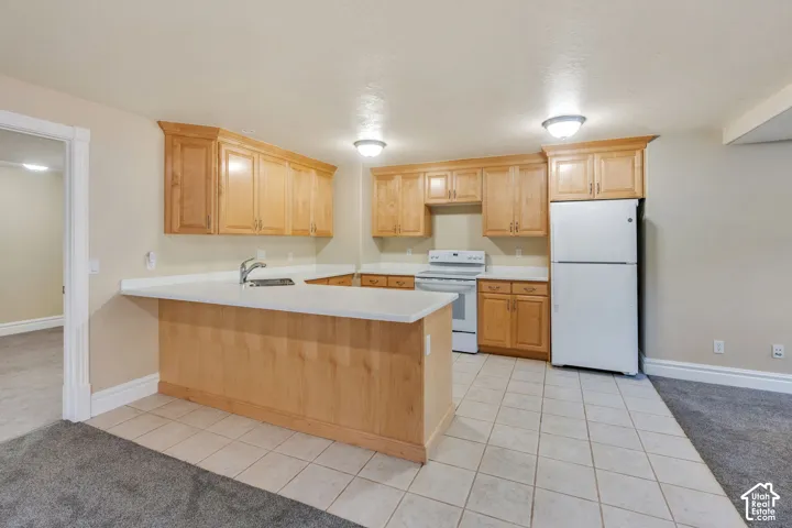 Kitchen featuring wood cabinetry, white countertops, a stainless steel sink, a white electric range, and a white refrigerator
