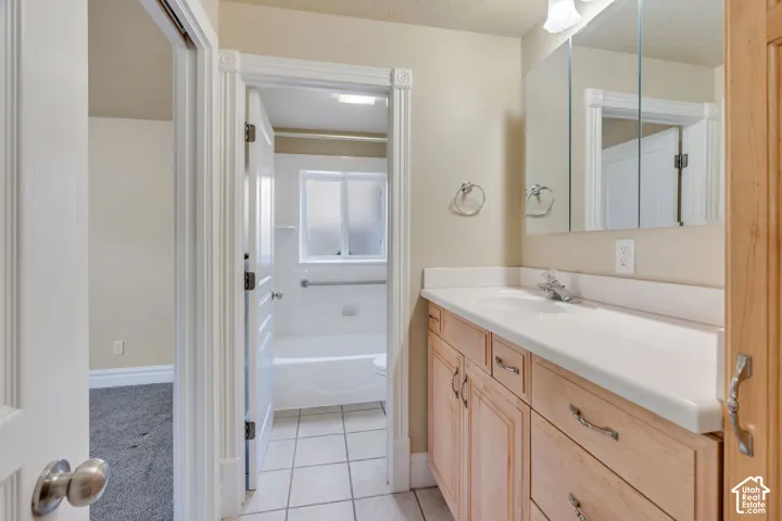 Bathroom vanity with a single basin sink, light wood cabinetry, and a mirrored medicine cabinet