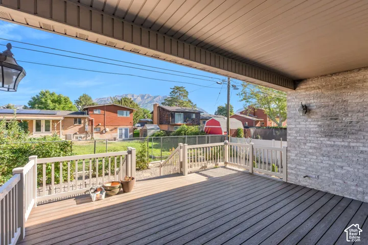 Expansive covered deck featuring composite decking, white railings, and an exterior wall with light-colored brick