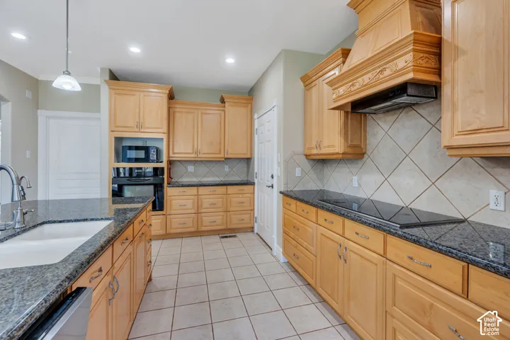 Kitchen featuring wood-finish cabinetry, dark speckled countertops, a built-in oven, and a cooktop